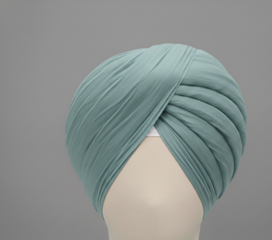 Teal turban on a mannequin head against a gray background